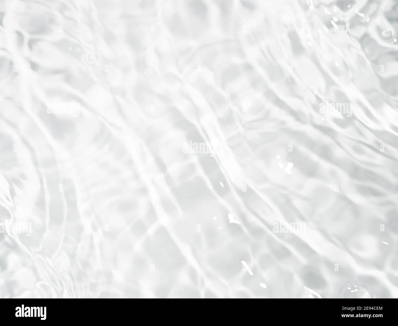Verschwommenes Wellenwasser auf weißem Hintergrund. Schatten des Wassers auf Sonnenlicht. Modell für Produkt-, Spa- oder Reisehintergrund. Marmor Wasseroberfläche als Hintergrund Tapete Stockfoto