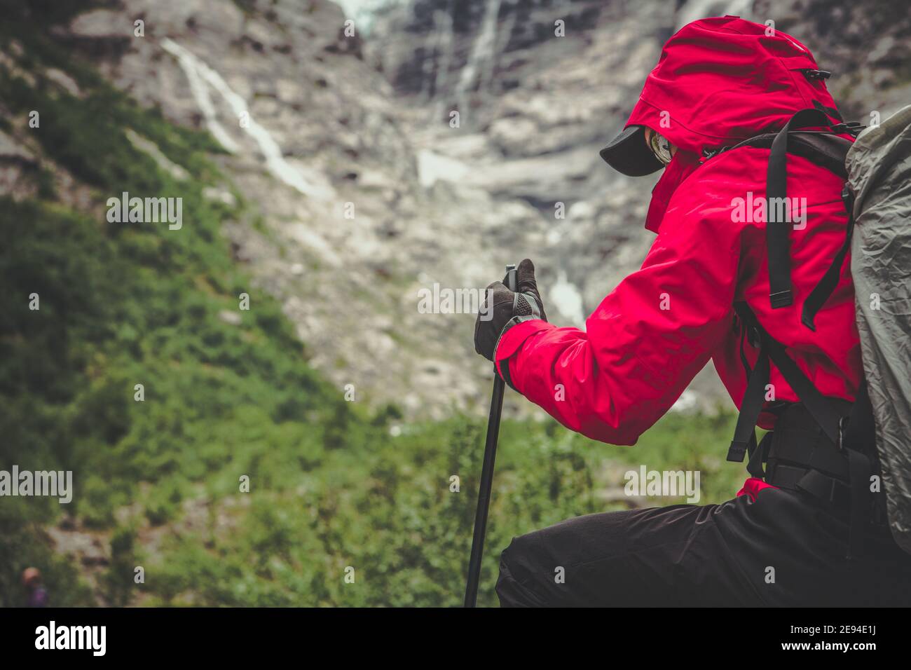 Alpine Trailhead Wanderer in Red Raincoat kurze Pause vor dem Angriff Summit of the Trail. Outdoor, Sport und Erholung Theme. Stockfoto