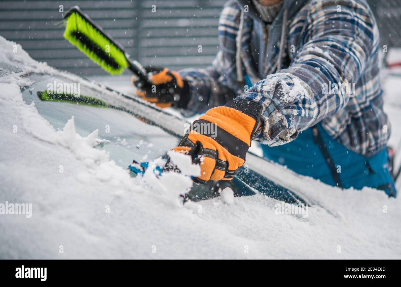 Kaukasischer Fahrer Entfernen von Schnee und Eis aus seinem Auto Windschutz. Extreme Wintersaison Wetter und die Auto-Wartung. Fahrzeugdesign. Stockfoto