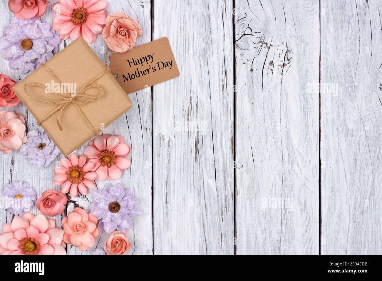 Seitenrand von Papierblumen mit Muttertag Geschenkbox Und Tag vor einem rustikalen weißen Holz Hintergrund Stockfoto