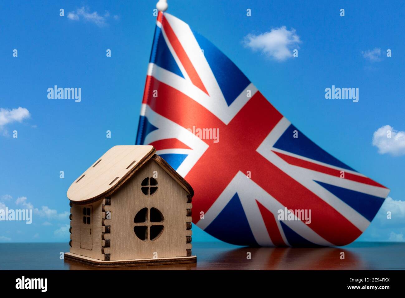 Kleines Holzhaus und Großbritannien Flagge, Himmel auf Hintergrund. Immobilienkonzept, Platz kopieren Stockfoto