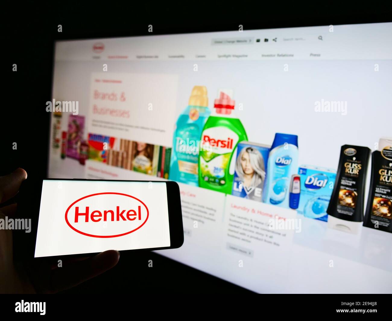 Person, die ein Mobiltelefon mit dem Logo des deutschen Chemie- und Konsumgüterunternehmens Henkel vor der Webseite hält. Konzentrieren Sie sich auf den Telefonbildschirm. Stockfoto