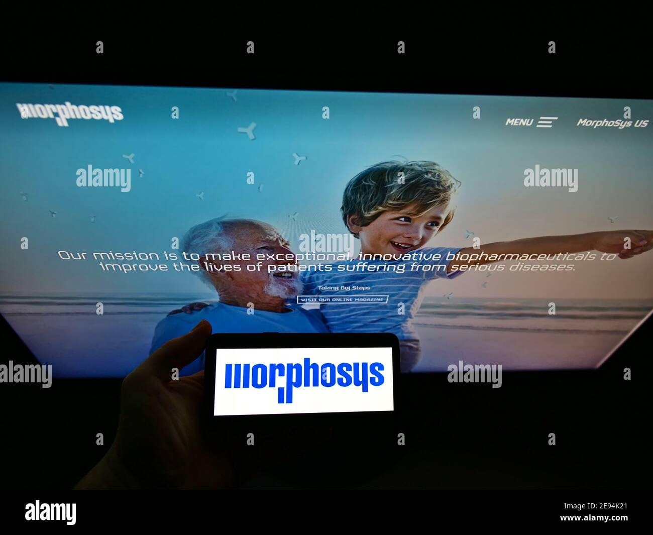 Person mit Mobiltelefon mit Logo des deutschen Biotechnologieunternehmens MorphoSys AG auf dem Display mit Business-Webseite. Fokus auf Telefonbildschirm. Stockfoto