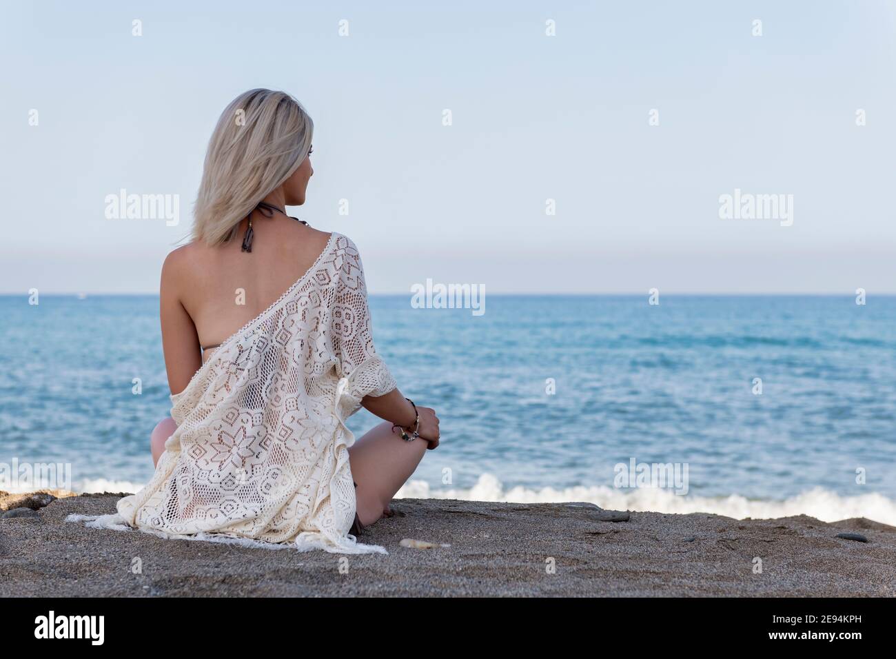 Eine Person, die an einem Strand sitzt. Hochwertige Fotos Stockfoto