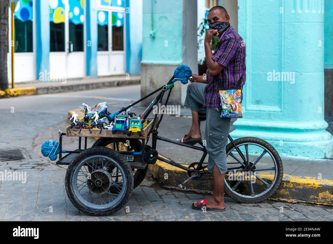 Selbstständiger kubanischer Mann, der hausgemachte Plastikspielzeug verkauft. Er trägt Gesichtsmasken, wie es die Zeit der Covid-19 ist Stockfoto