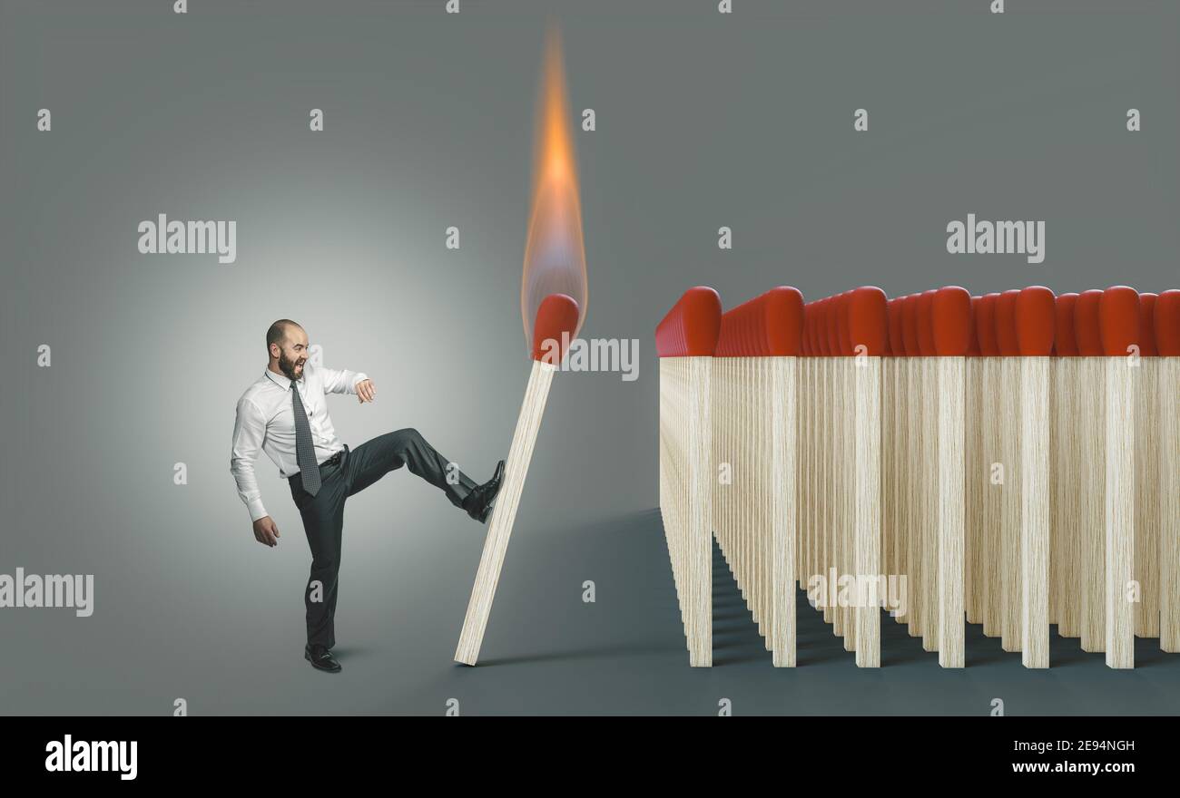 Geschäftsmann tritt ein brennendes Spiel, um eine Kettenreaktion zu entzünden. Gefahr Konzept. Stockfoto