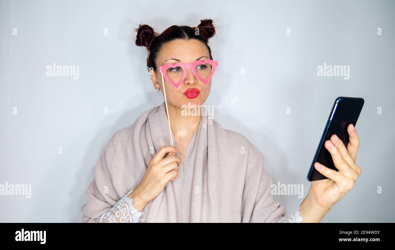 Frau mit rosa Herzbrille nutzt ihr Telefon für einen Videoanruf. Stockfoto