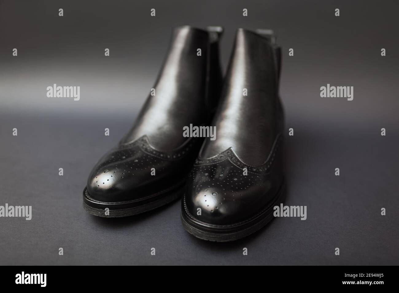 Schuhe, chelsea Lederstiefel für Herren. Herren Winter-, Herbst- oder Frühlingsmode. Schwarze Schuhe mit Perforation auf schwarzem Hintergrund. Verkauf Stockfoto