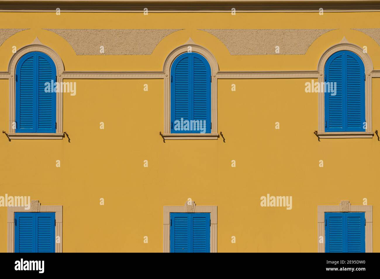 Fassade mit gelber Wand und blauen Fenstern für Hintergründe Stockfoto