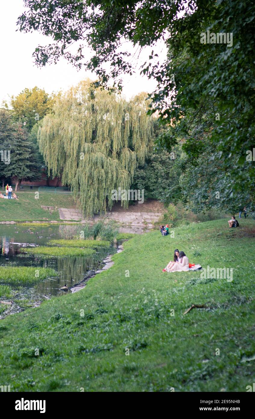 Lviv, Ukraine - 28. August 2020: Menschen, die in der Nähe von See in der Stadt öffentlichen Park Kopie Platz. Blick auf Enten Stockfoto