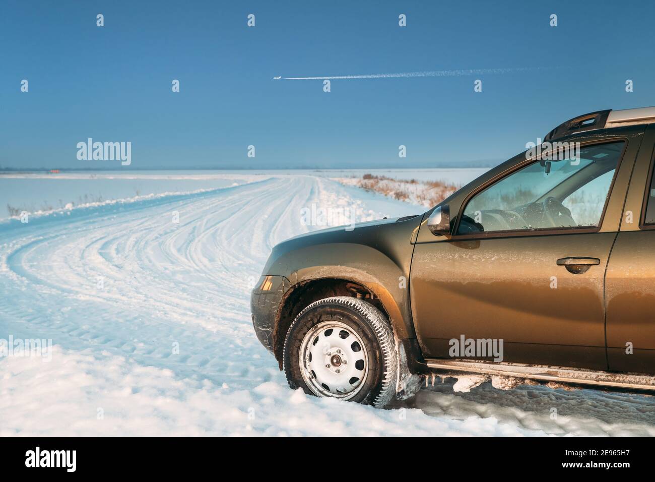 Gefrorene und grungy SUV Auto auf Winter Snowy Field Landschaft geparkt. Veränderter Himmel Mit Flugzeug Stockfoto