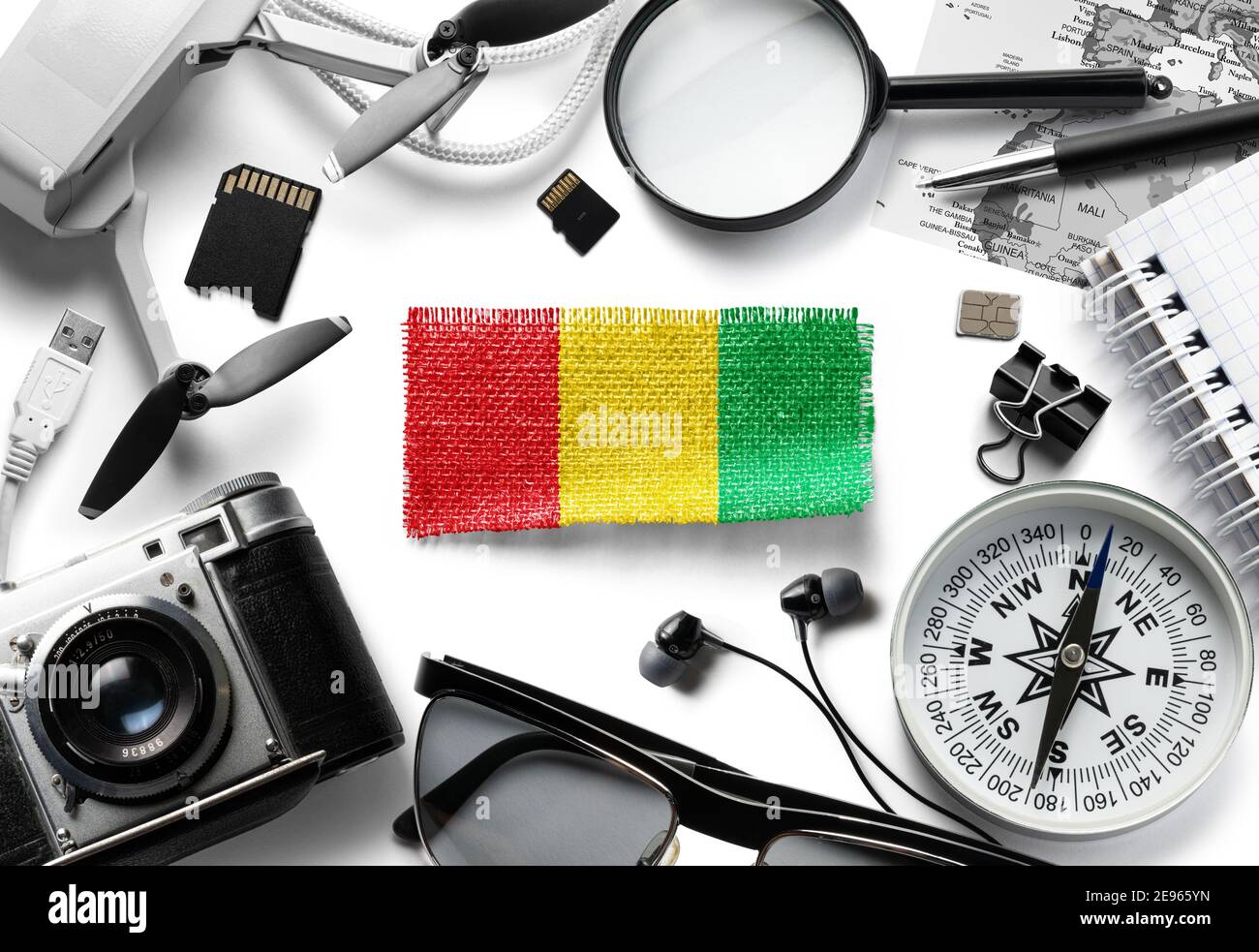 Flagge von Guinea und Reiseaccessoires auf weißem Hintergrund. Stockfoto