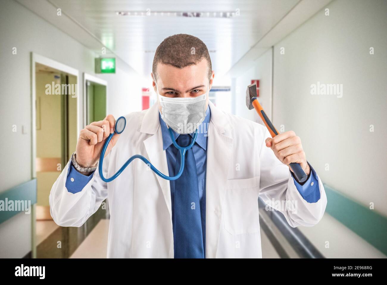 Schlecht maskierten Arzt hält einen Hammer, covid Coronavirus Konzept Stockfoto