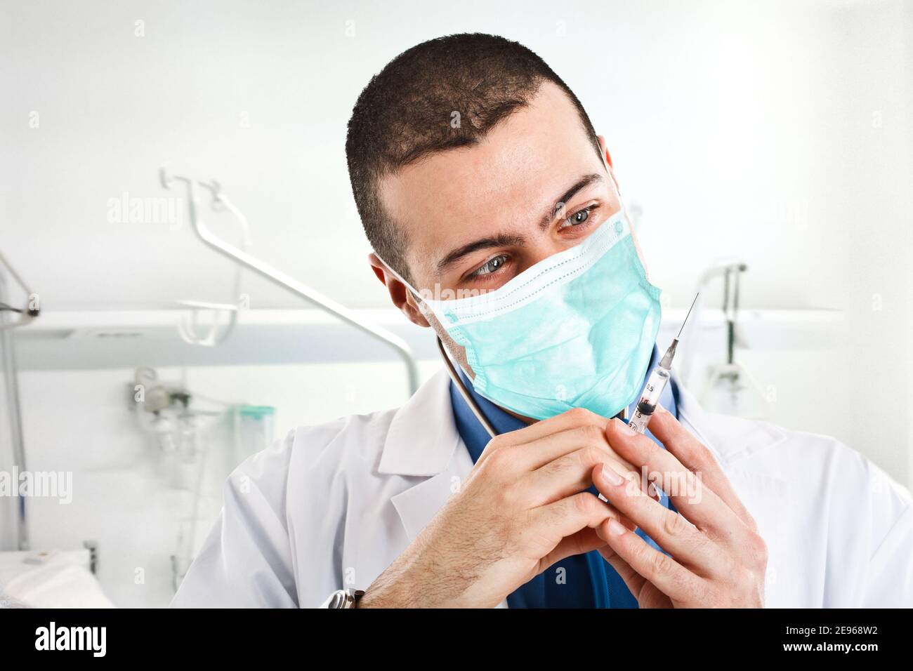 Gruseliger Arzt, der eine Spritze anschaut, Coronavirus covid Impfstoff Konzept Stockfoto