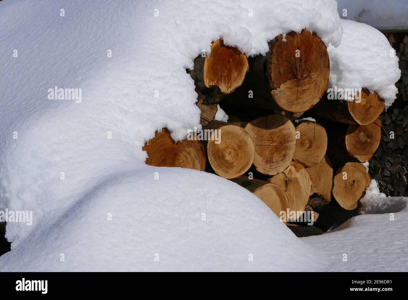 Tief eingeschneite Baumstämme auf dem Gelände eines Zimmermanns Workshop im kalten Winter Stockfoto