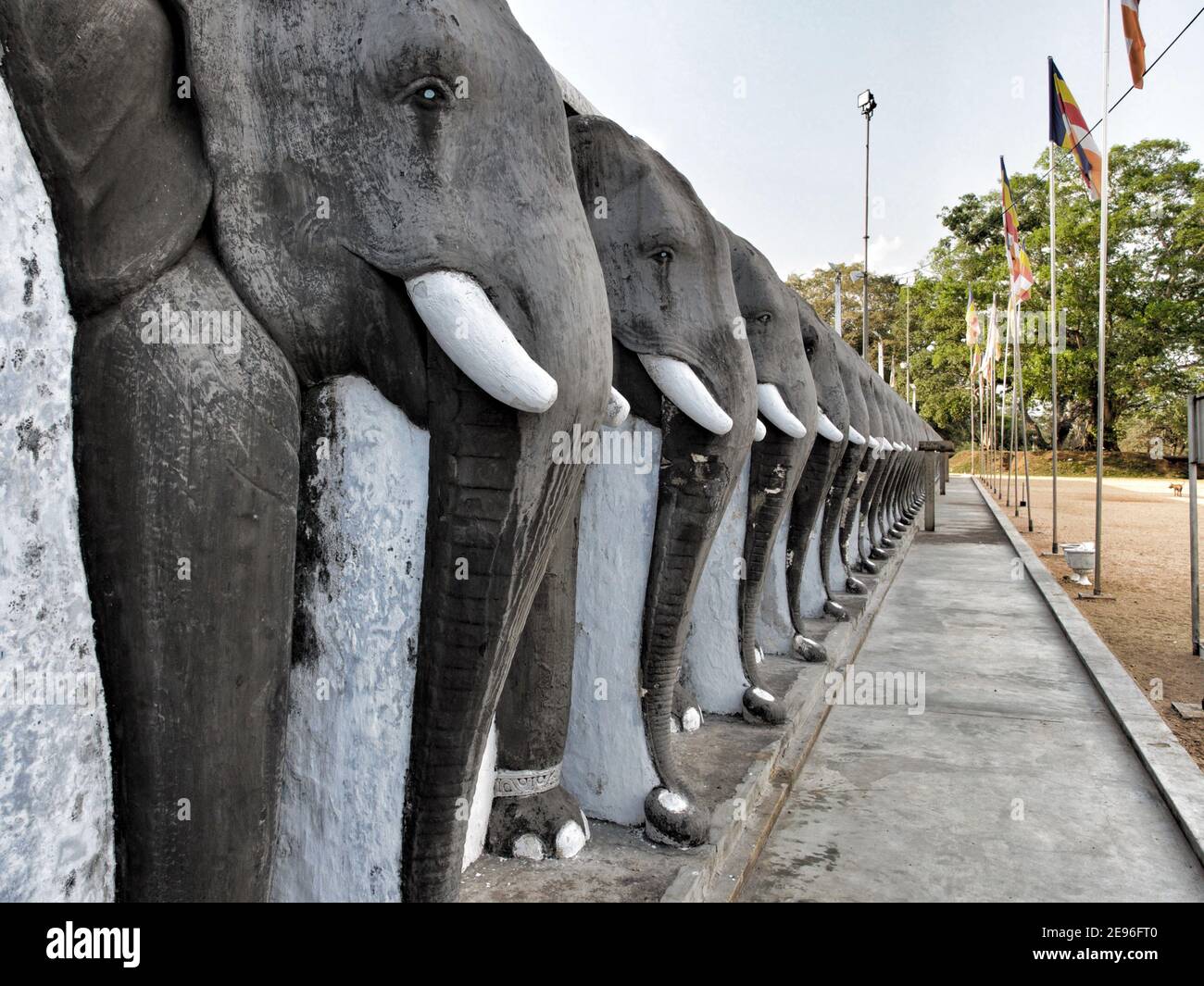 ANURADHAPURA, SRI LANKA - 9. März 2019: Linie von geschnitzten Elefanten schützen die Ruwanwelisaya Stupa in der heiligen Stadt Anuradhapura. Horizontale Aufnahme. Stockfoto