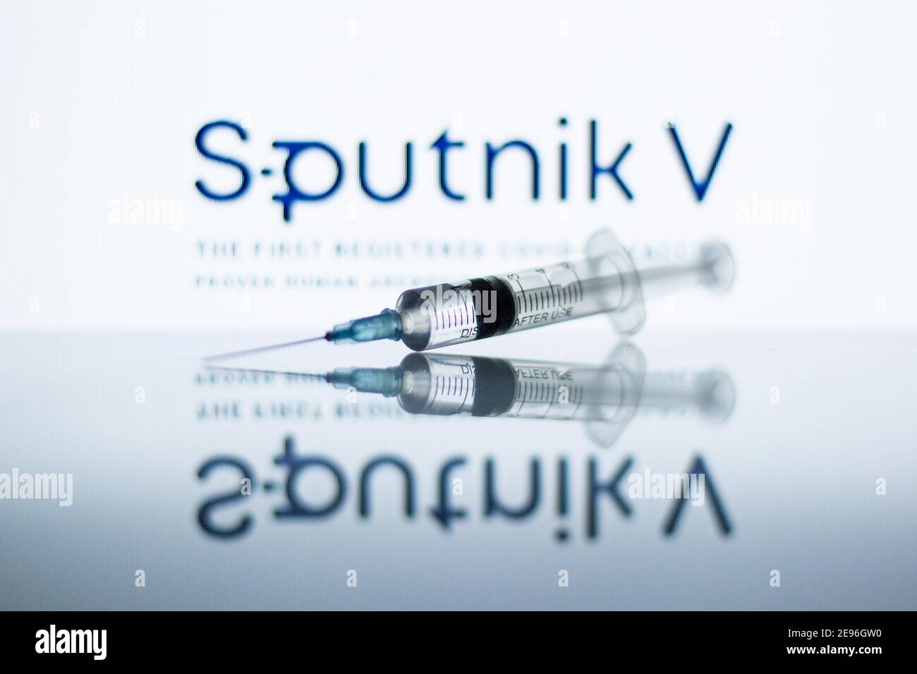 In dieser Abbildung ist eine medizinische Spritze vor dem Sputnik V Logo zu sehen. Stockfoto