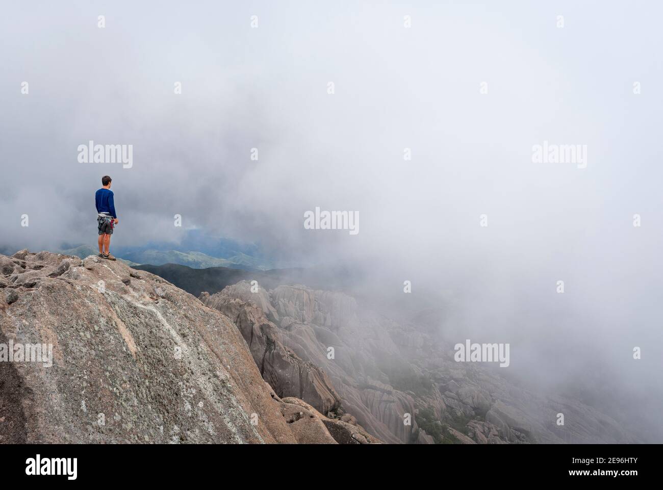 Mann auf der Spitze eines Berggipfens auf einem Nebliger Tag Stockfoto