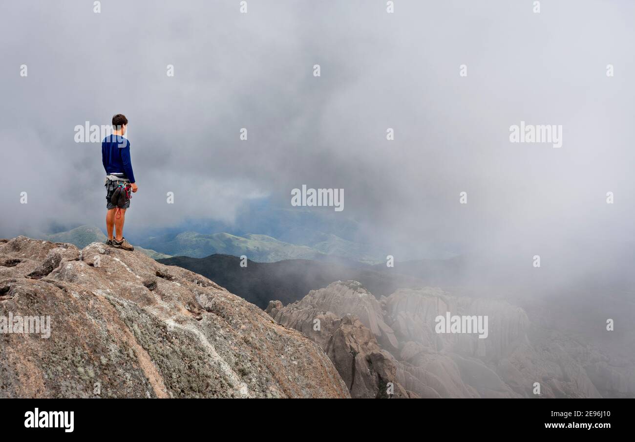 Mann auf der Spitze eines Berggipfens auf einem Nebliger Tag Stockfoto