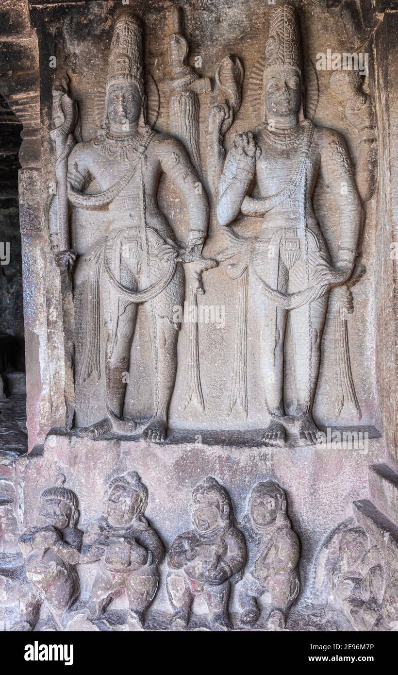 Aihole, Karnataka, Indien - 7. November 2013: Ravanaphadi Cave Shiva Temple. Nahaufnahme von 2 grauen Stein stehende menschliche Figuren Skulpturen, über einer Reihe von Stockfoto