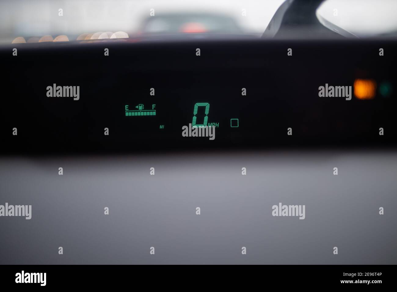 Digitaler Tachometer, der unter einer nassen Windschutzscheibe auf dem Armaturenbrett leuchtet Stockfoto