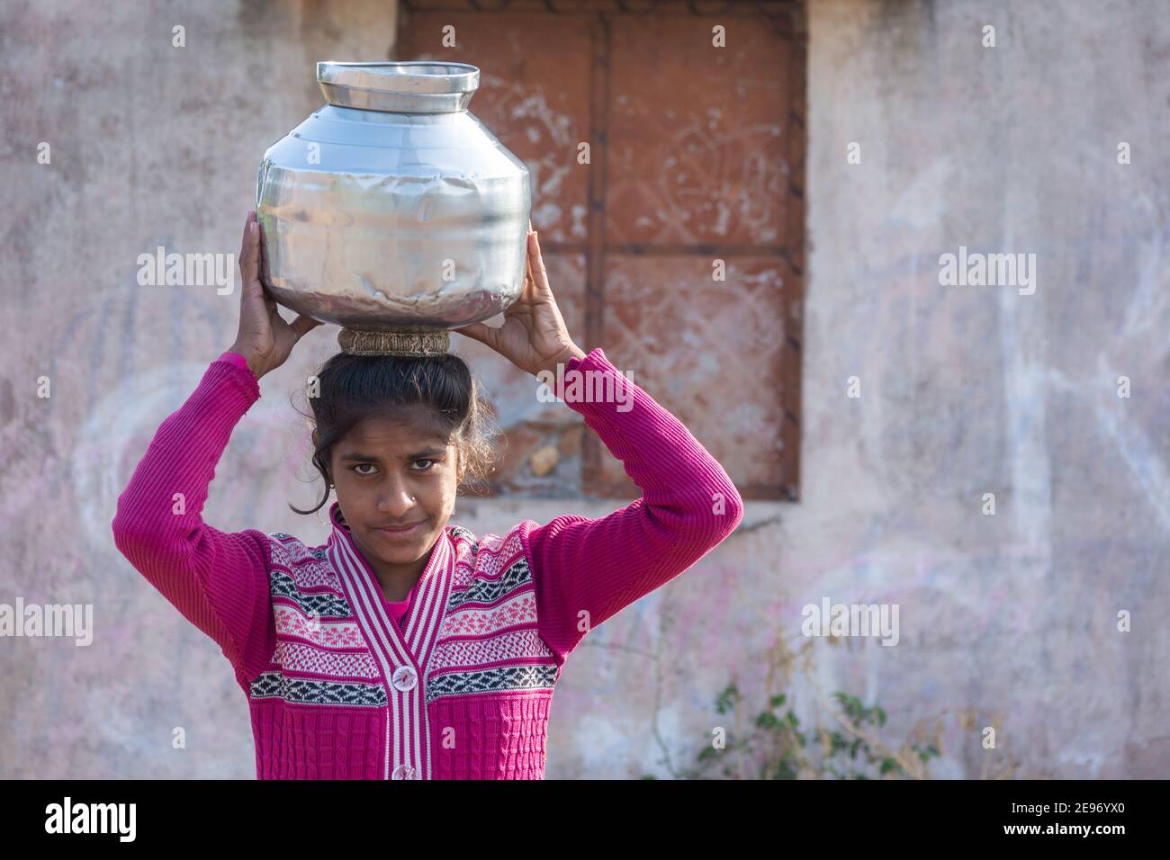 TIKAMGARH, MADHYA PRADESH, INDIEN - 23. JANUAR 2021: Ein nicht identifiziertes indisches Dorfmädchen trägt Wasser auf ihren Köpfen in traditionellen Töpfen aus Brunnen. Stockfoto