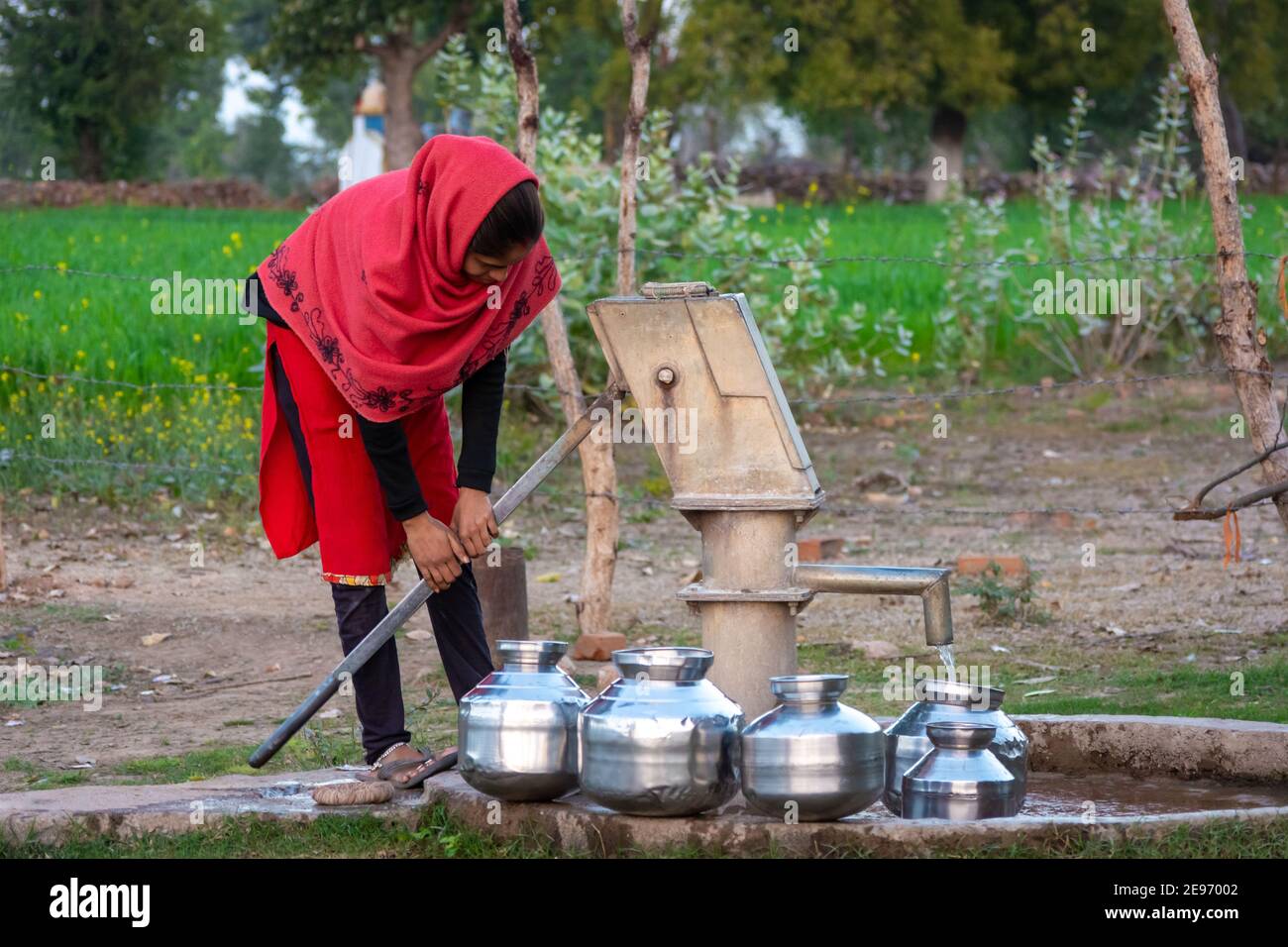TIKAMGARH, MADHYA PRADESH, INDIEN - 23. JANUAR 2021: Nicht identifiziertes indisches Mädchen, das Handpumpe für Trinkwasser verwendet. Stockfoto