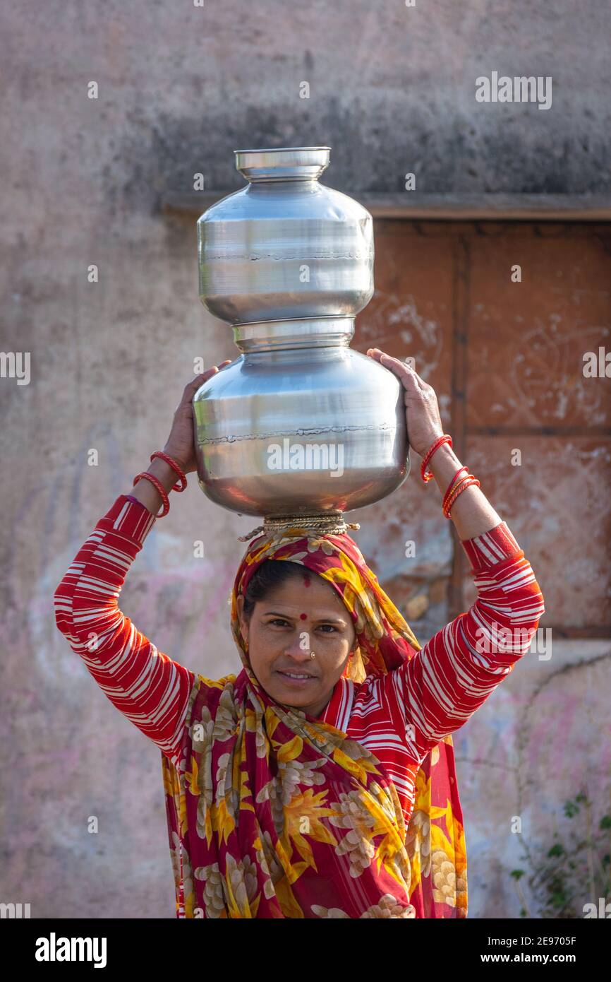 TIKAMGARH, MADHYA PRADESH, INDIEN - 23. JANUAR 2021: Eine indische Frau, die einen Behälter mit Wasser auf dem Kopf trägt. Stockfoto