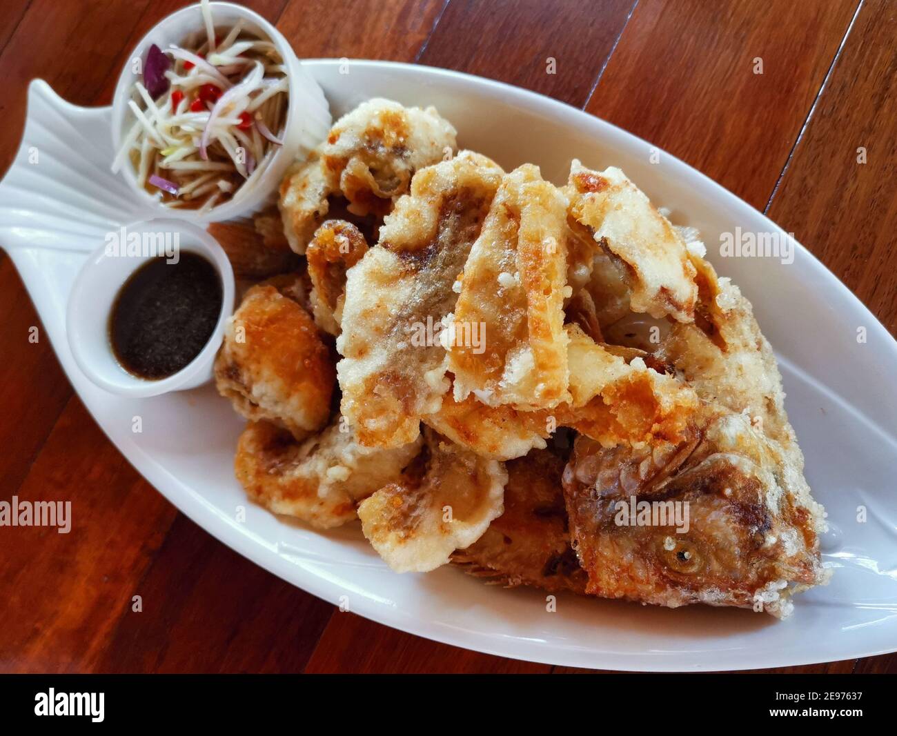 Gebratener Seebarsch mit Fischsauce. Gebratene Fischfilets die Schale mit dem Kopf und dem Fischbein anrichten. Thailändisches Essen. Stockfoto