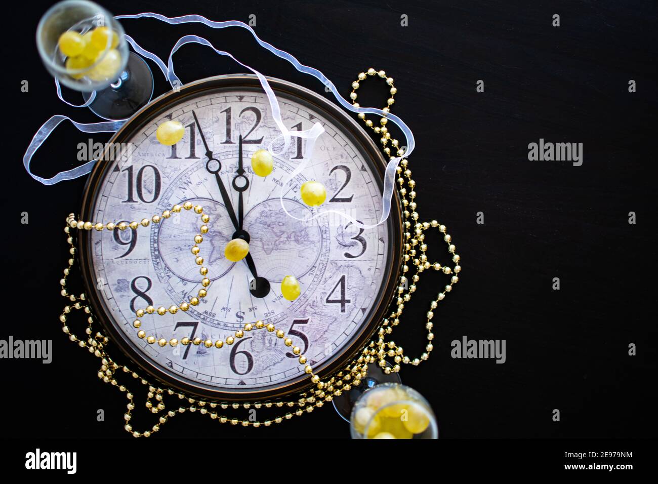 Ein Zifferblatt vor Mitternacht am Silvesterabend in Spanien mit zwei Sektflöten mit zwölf Trauben Stockfoto
