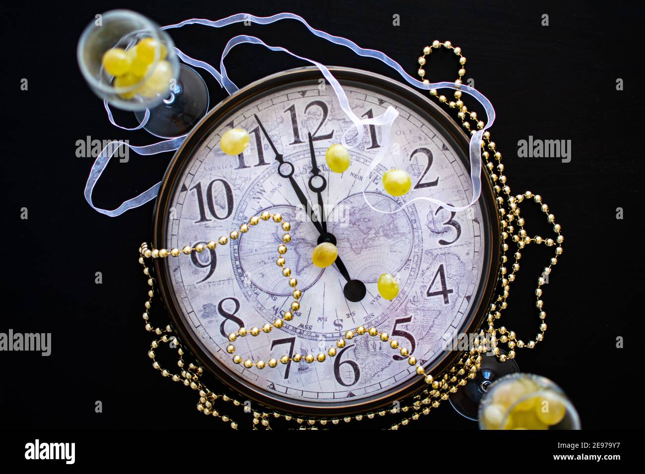 Ein Ziffernblatt, das kurz vor Mitternacht über neue Jahre zeigt eve in Spanien mit zwei Sektflöten mit zwölf Trauben Stockfoto