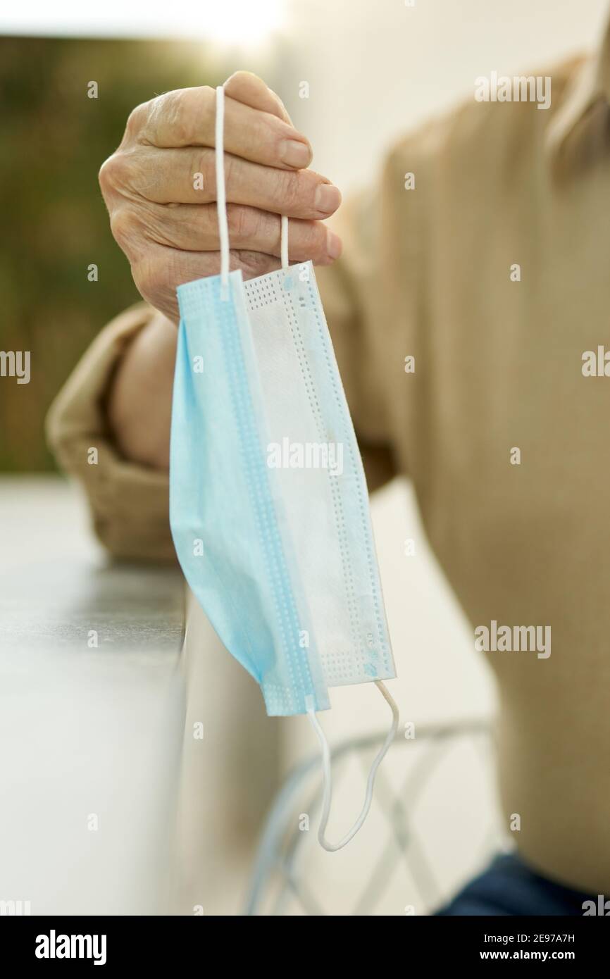 Zugeschnittenes Foto einer Person, die eine OP-Maske am hält Schleife Stockfoto