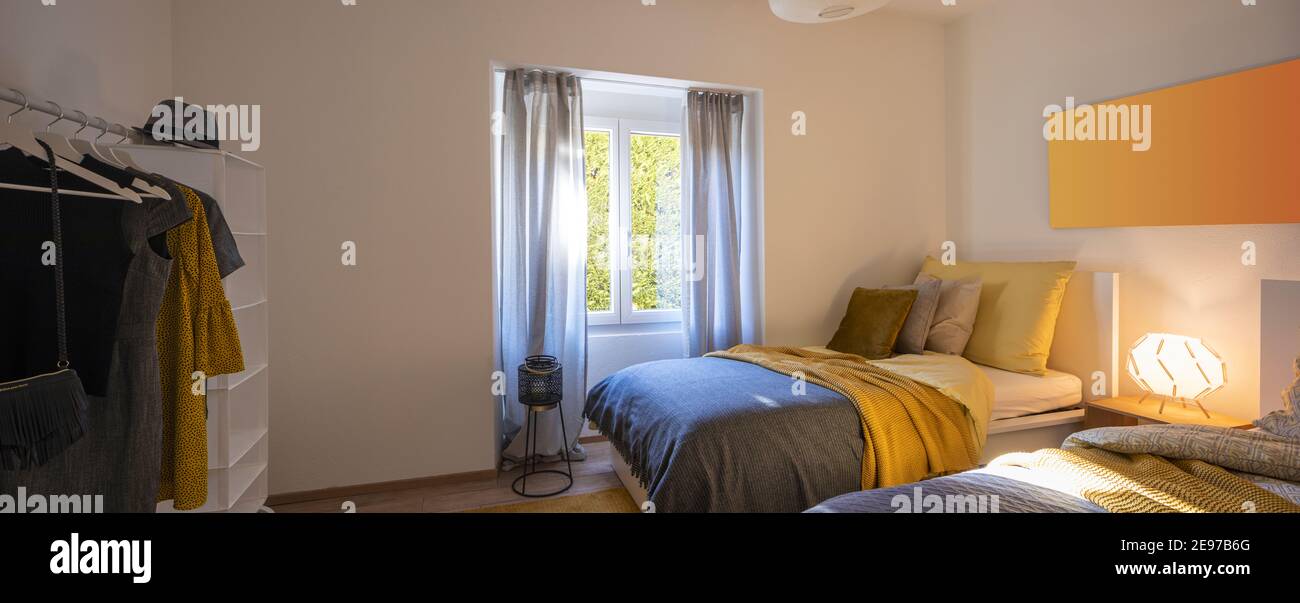 Modernes Schlafzimmer mit zwei Einzelbetten mit sauberer Bettwäsche und großem Kopfkissen darüber. Weiße Wand. Niemand drinnen. Stockfoto