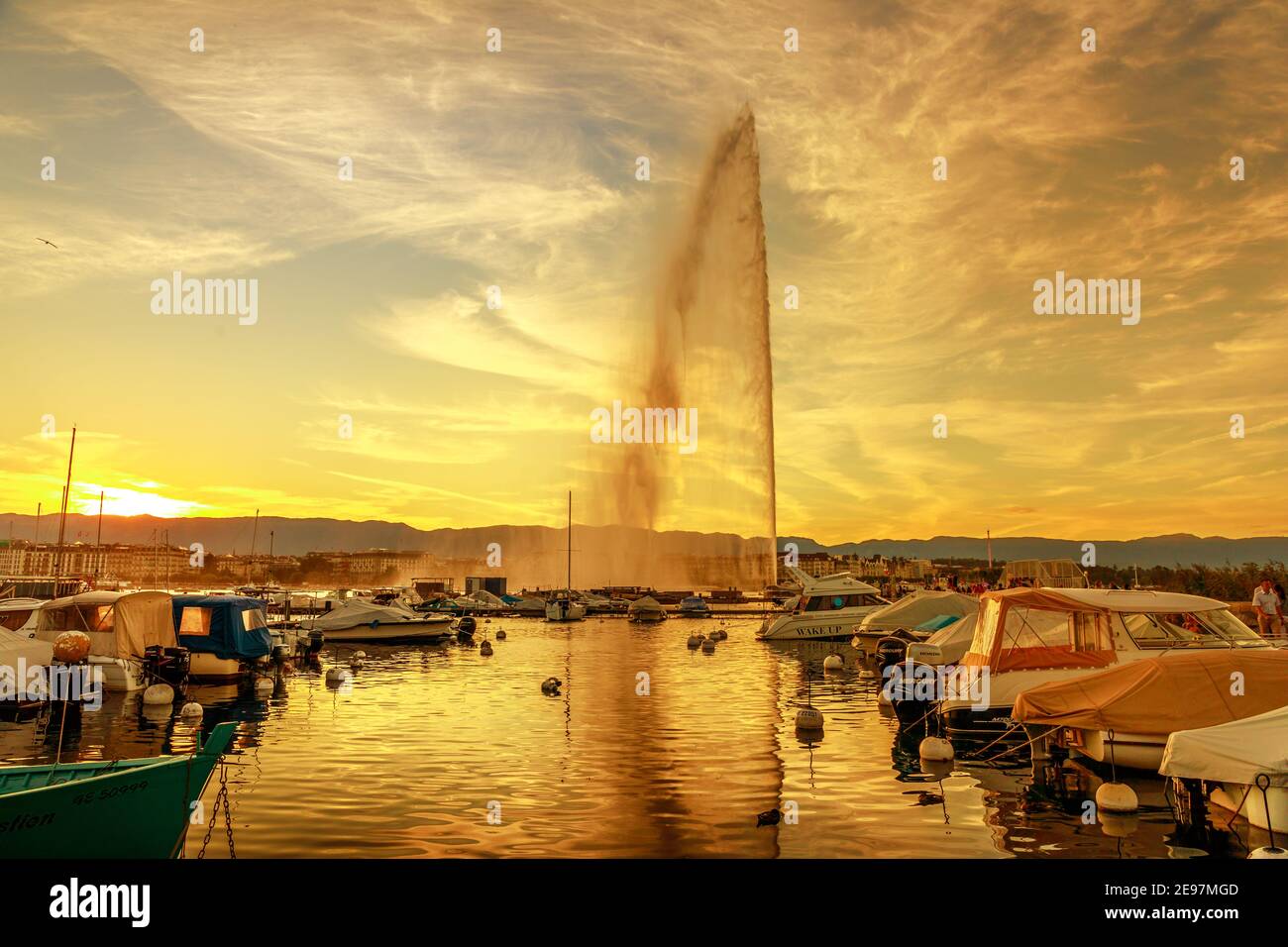 Genf, Schweiz - 14. Aug 2020: Blick auf den Jet d'Eau Brunnen, Symbol von Genf bei Sonnenuntergang. Boote und Segelboote im kleinen Hafen von Jetee des Stockfoto