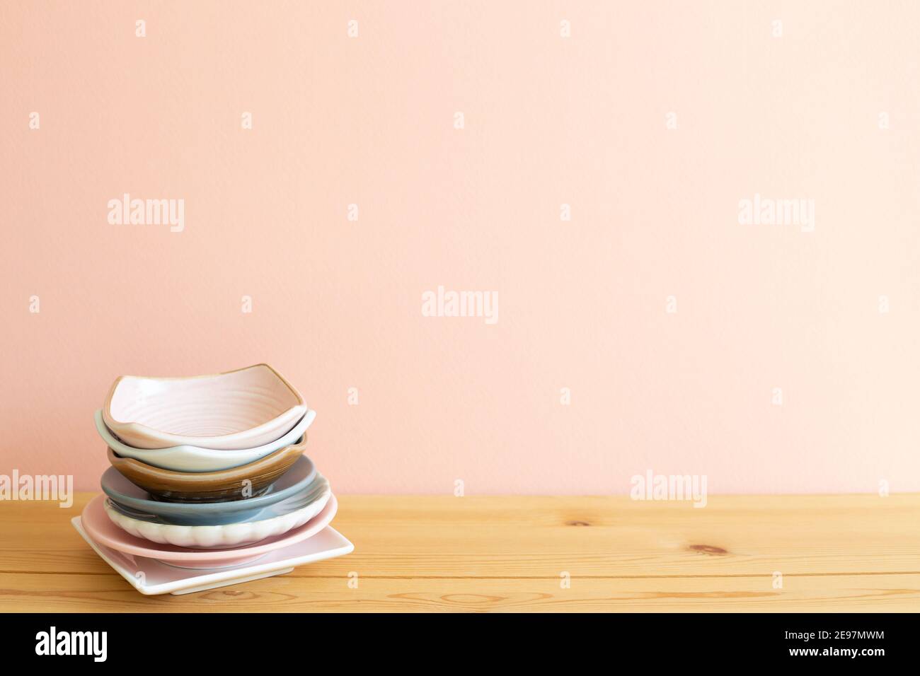Stapel von bunten Geschirr auf Holztisch. Rosa Hintergrund Stockfoto