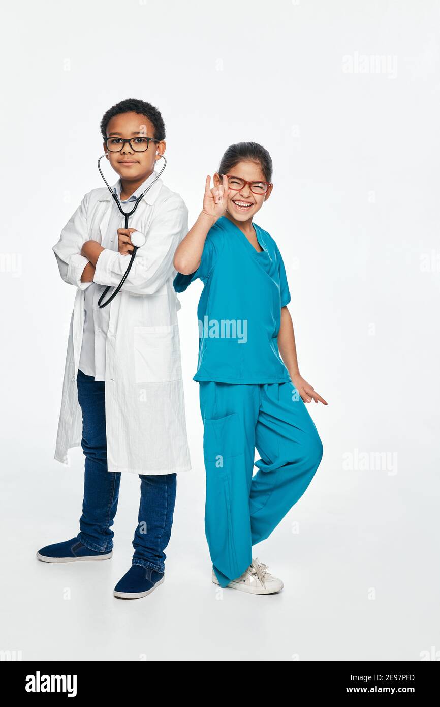 Fun Kinder tragen eine medizinische Uniformen auf weißem Hintergrund. Zwei Kinder spielen medizinisches Personal und wählen einen medizinischen Beruf Stockfoto