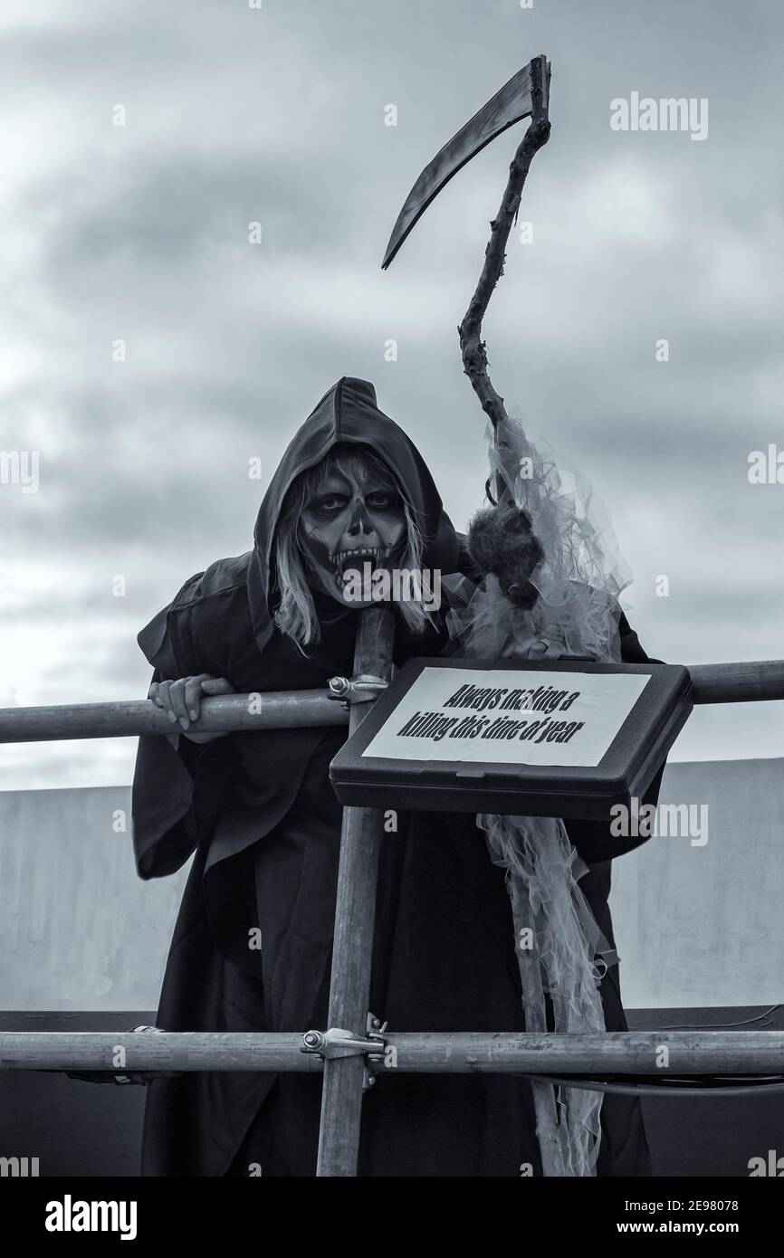 Immer ein Töten dieser Zeit des Jahres, grimmig reaper schwingende Sense nimmt an Weymouth Karneval in Weymouth, Dorset UK im August Stockfoto