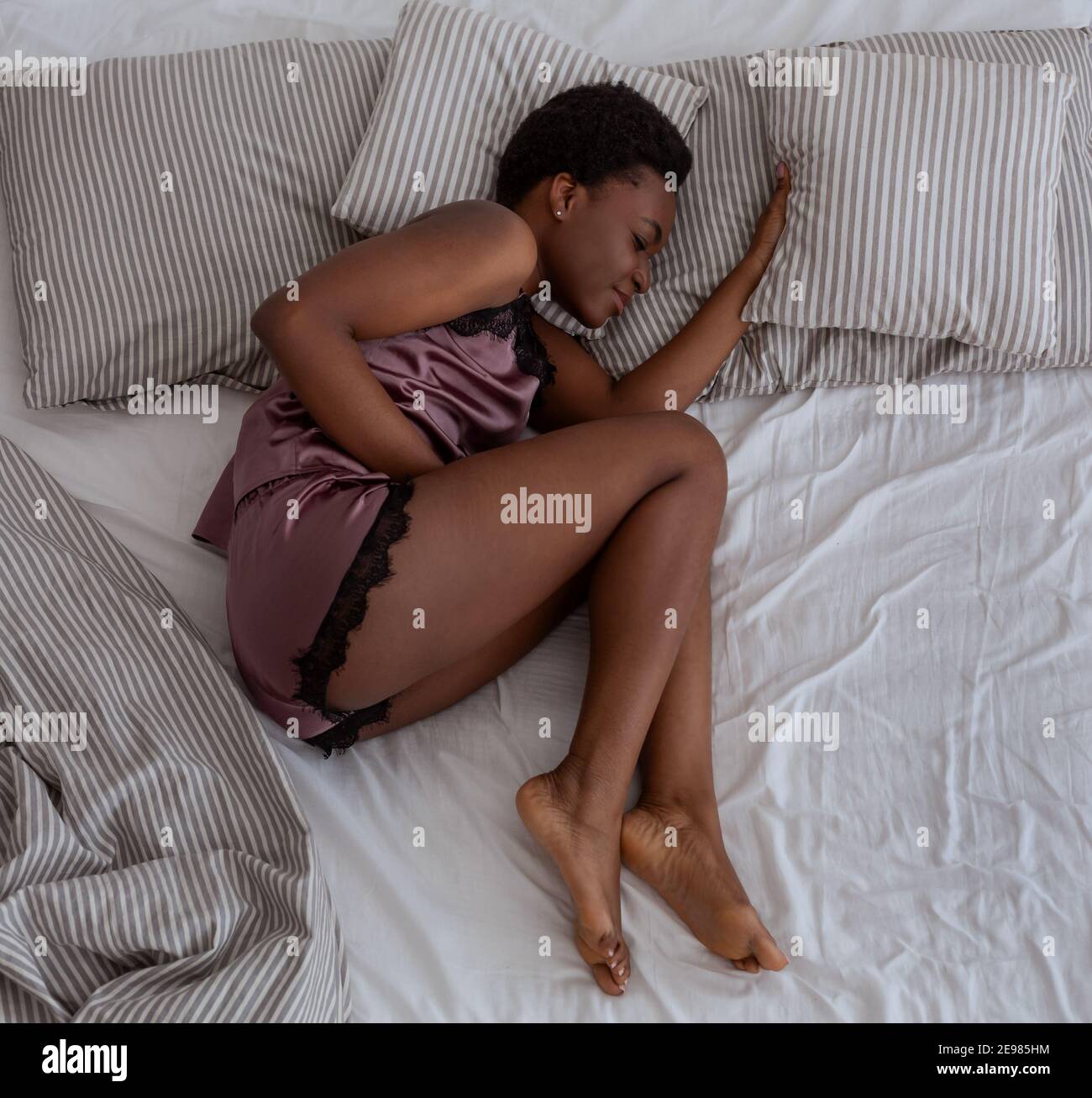 Unglücklich gestresst Millennial african american Frau im Bett liegend verdoppelt mit schmerzhaften Magen Gefühl, ungesund Stockfoto