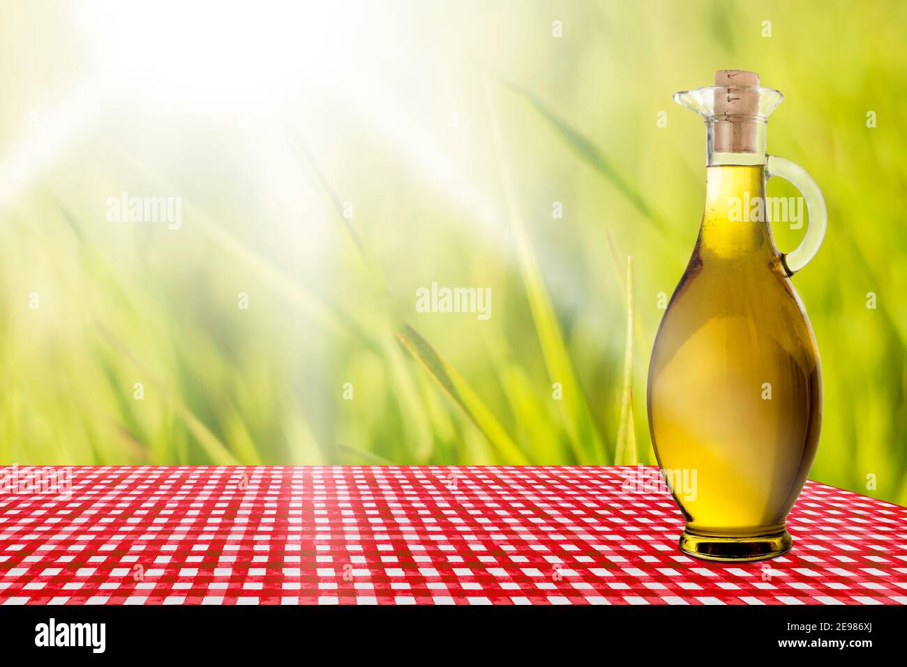 Flasche Olivenöl extra vergine auf einem rot karierten Tischdecke an einem sonnigen Tag im Freien Stockfoto