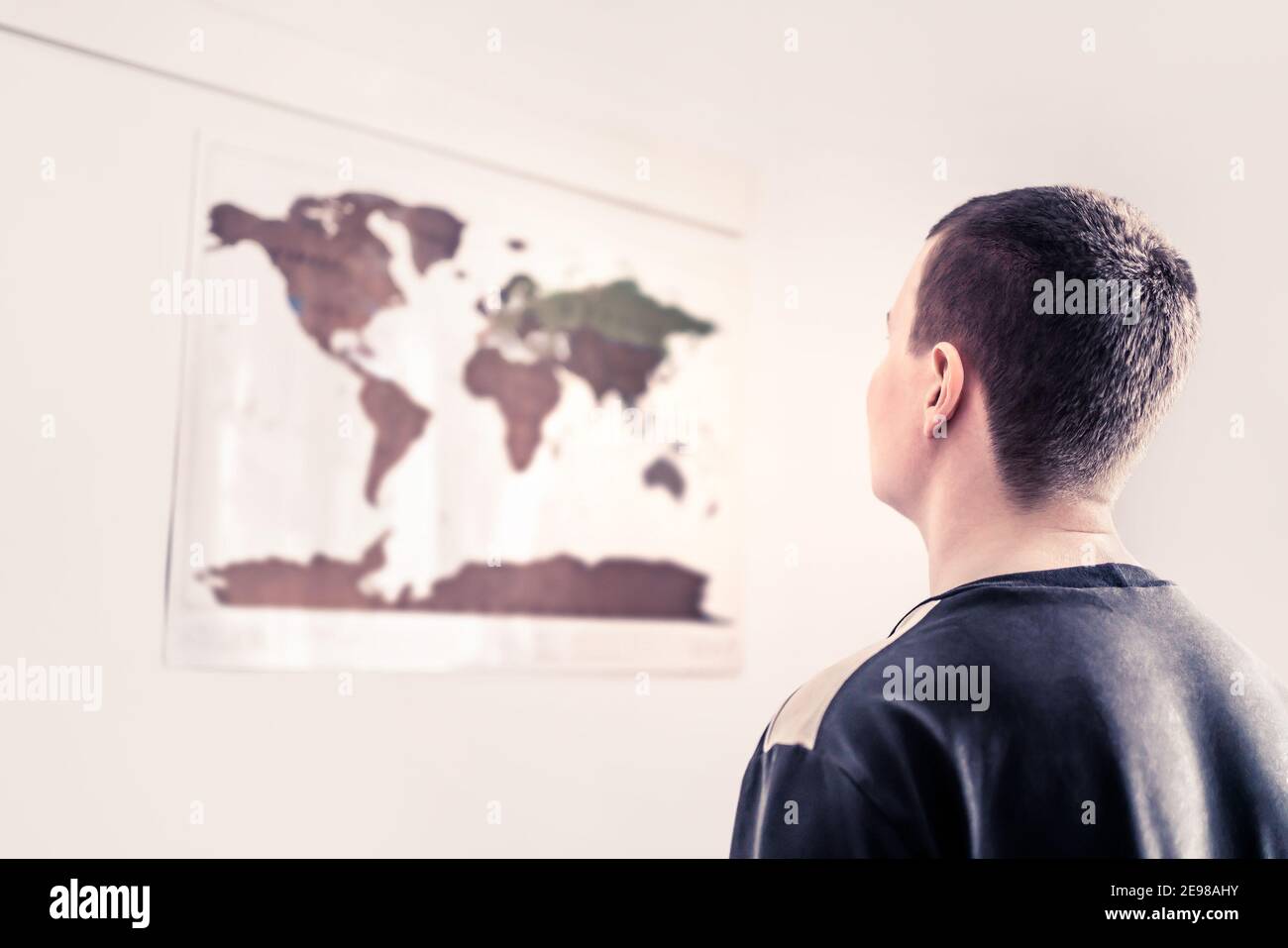Mann, der auf eine Weltkarte an der Wand schaut. Denken Sie an die sich verändernde Umwelt, ungewisse Zukunft oder weltweite Probleme. Globale Gleichheit, Menschenrechte. Stockfoto