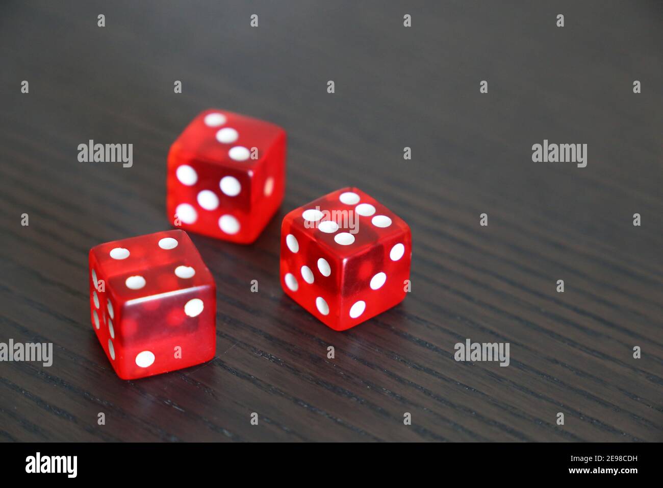 Rote Würfel auf dunklem Holztisch. Hintergrund für Casino-Spiele, Glücksspiel, Glück oder Zufälligkeit Stockfoto