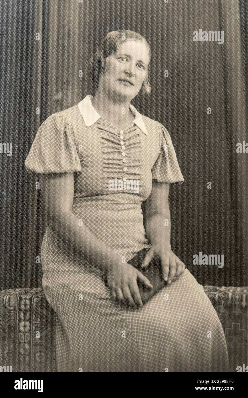 Deutschland - UM 1930er Jahre: Porträt einer Frau, die auf einer Bank im Atelier sitzt, Vintage Carte de Viste Foto aus der Art Deco-Ära Stockfoto