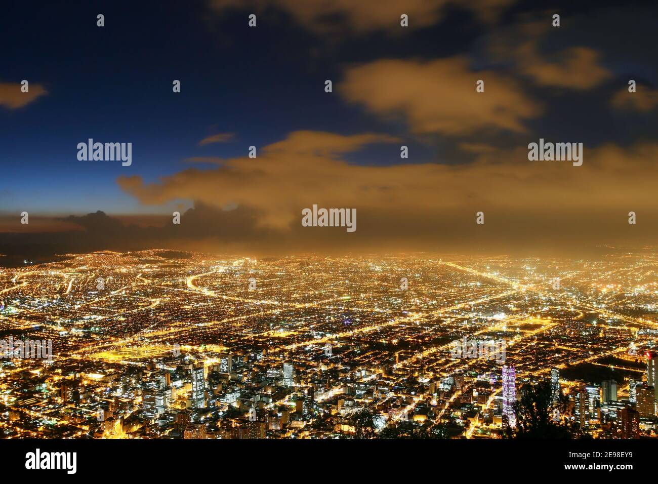 Schöne Luftaufnahme von Bogota Stadt bei Nacht mit Geschäftsgebäuden, Straßenlaternen, Alleen und Himmel in der Dämmerung mit Wolken im Hintergrund. Stockfoto