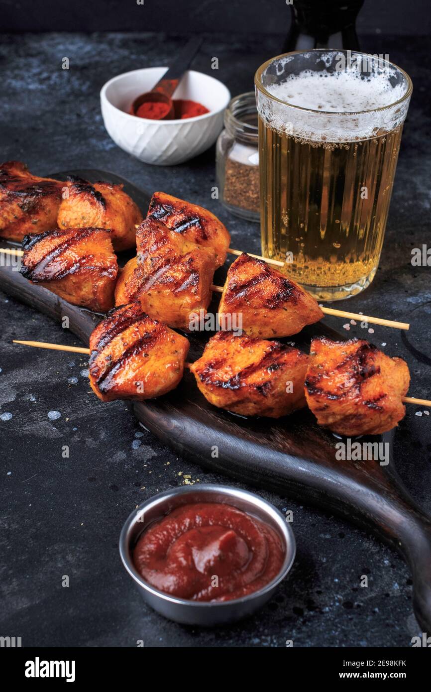 Einfach und lecker Chicken Kebabs. Gegrilltes Hähnchen auf Bambusspießen mit einem Getränk. Dunkler Hintergrund. Stockfoto