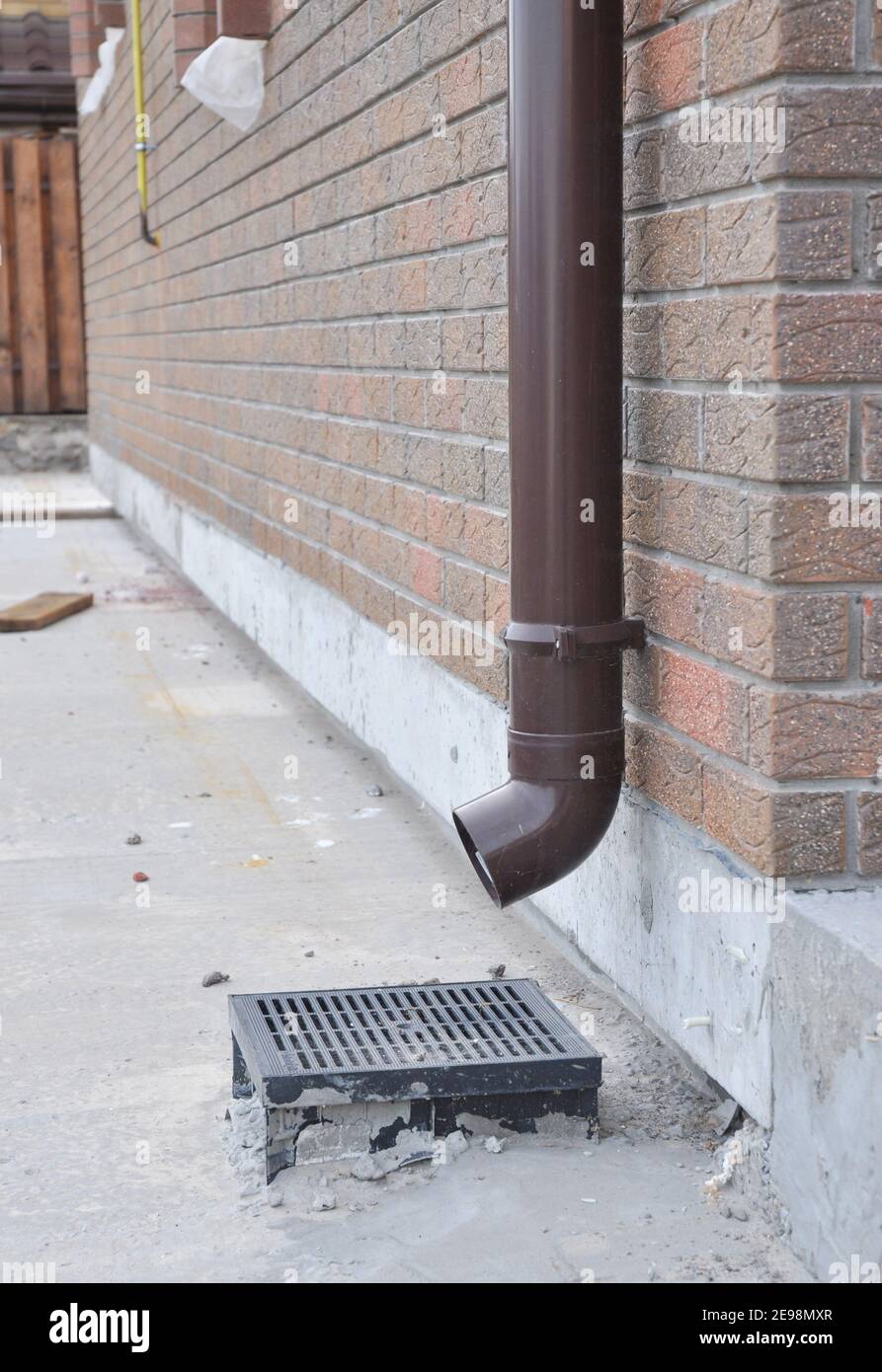 Installation Regenrinne Downauslauf Rohr für Dach Wasserablauf und Abdichtung Haus Fundamentwand. Kunststoff-Dachrinnen. Stockfoto
