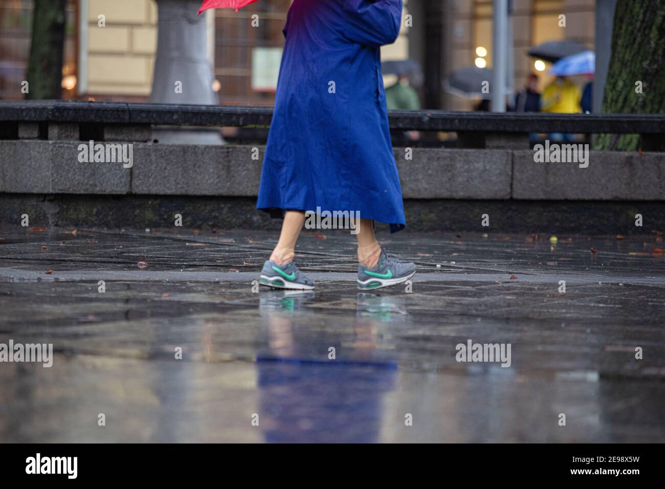 Lviv, Ukraine - 30. September 2020: Ältere Frau trägt Nike Sneakers und  roten Regenschirm zu Fuß auf regnerischen Straße Stockfotografie - Alamy