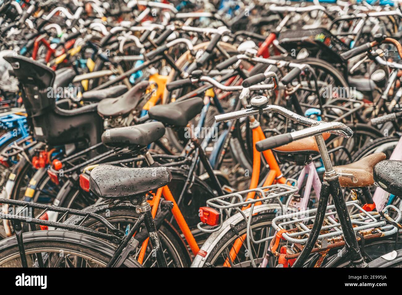 Fahrradparkplatz mit vielen Fahrrädern, regnerischer Tag, städtischer Kultverkehr in Amsterdam. Stockfoto