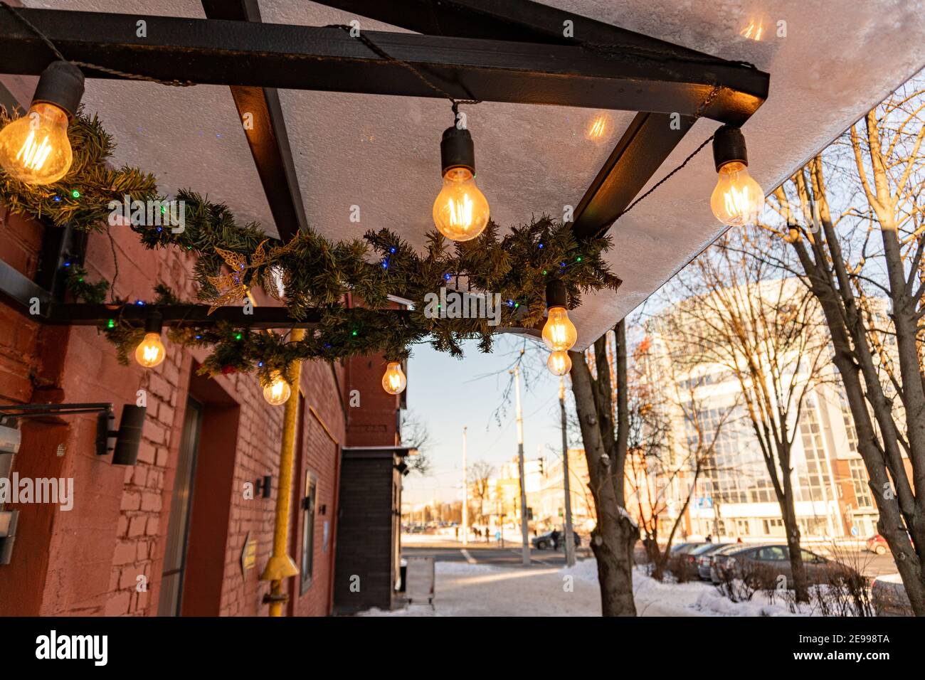 Minsk, Weißrussland - 01. Februar 2021: Der Baldachin des Cafés ist mit Edison-Glühbirnen geschmückt und leuchtet mit einem warmen gelben Licht Stockfoto