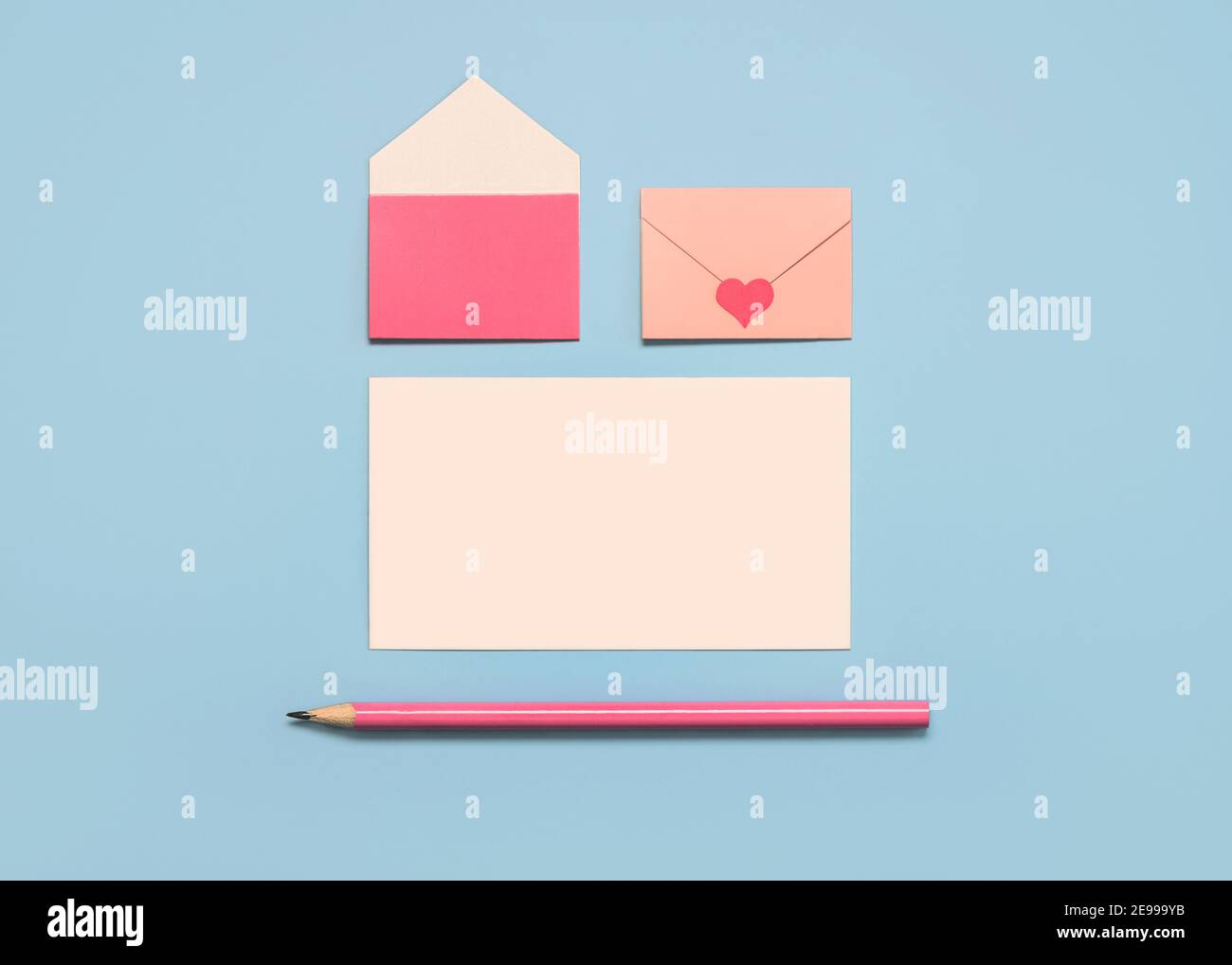 Alles Liebe zum Valentinstag.Papierumschläge mit weißer Karte und rosa Bleistift Auf blauem Hintergrund Stockfoto