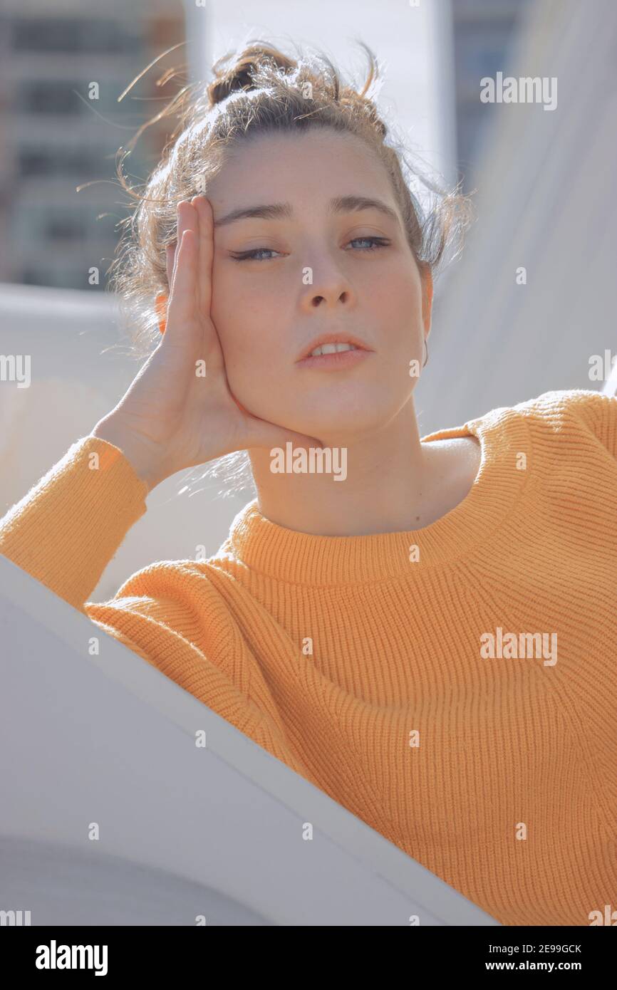 Nahaufnahme Bild einer jungen Frau mit einem gelben Pullover posiert vor der Kamera an einem sonnigen Tag im Freien. Frühjahrsfotografie 2021. Stockfoto